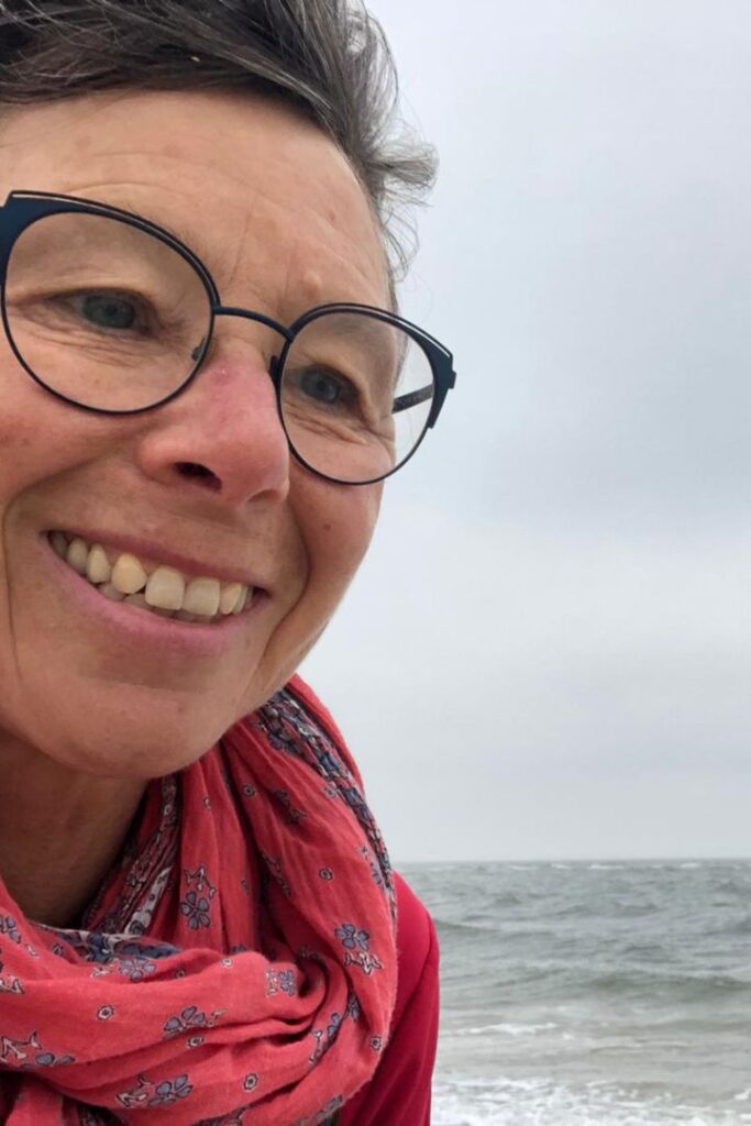 Susanne Lohse steht am Meer im Wind und freut sich des Lebens. Sie bietet Burnout Hilfe in Karlsruhe an.