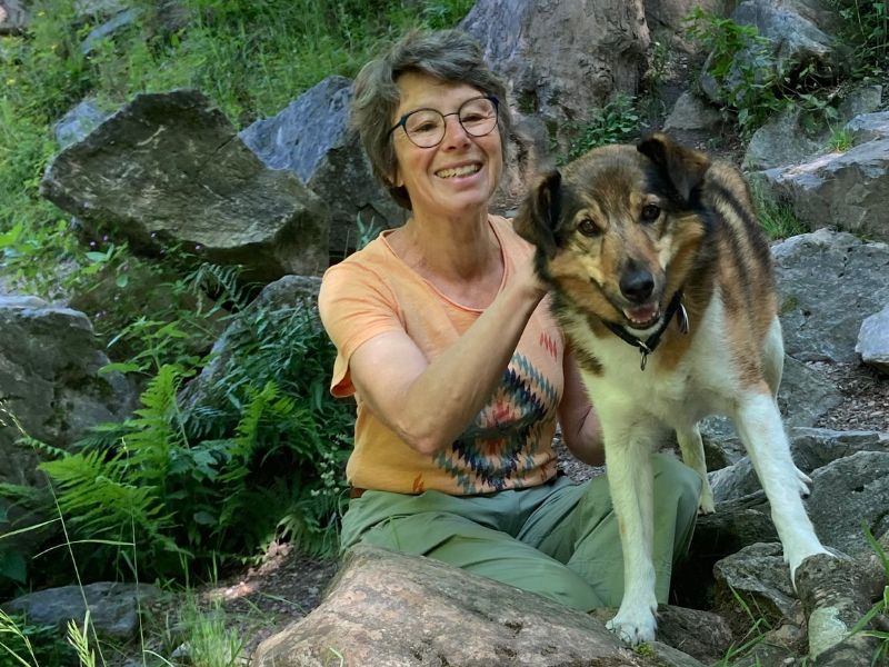 Susanne Lohse, voller Lebensfreude, mit ihrem Hund im Wald. Sie bietet Stressbewältigung in Karlsruhe an.