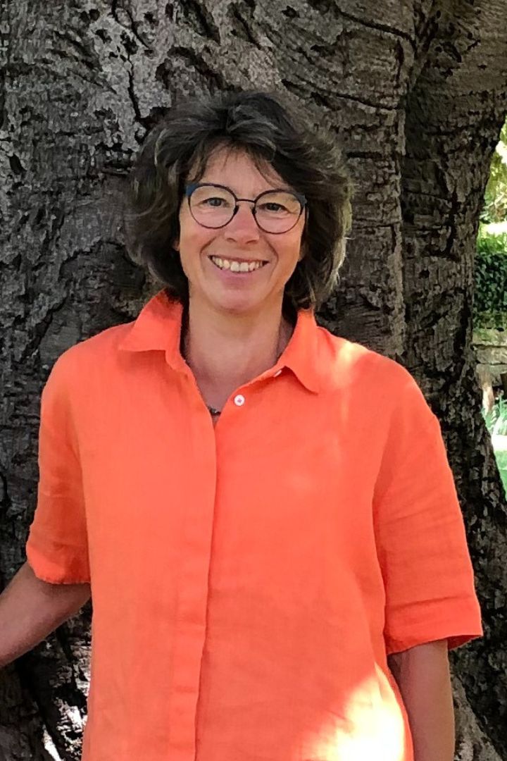 Sabine Lohse steht lächelnd vor einem Baum. Sie bietet Stressbewältigung in Karlsruhe an.